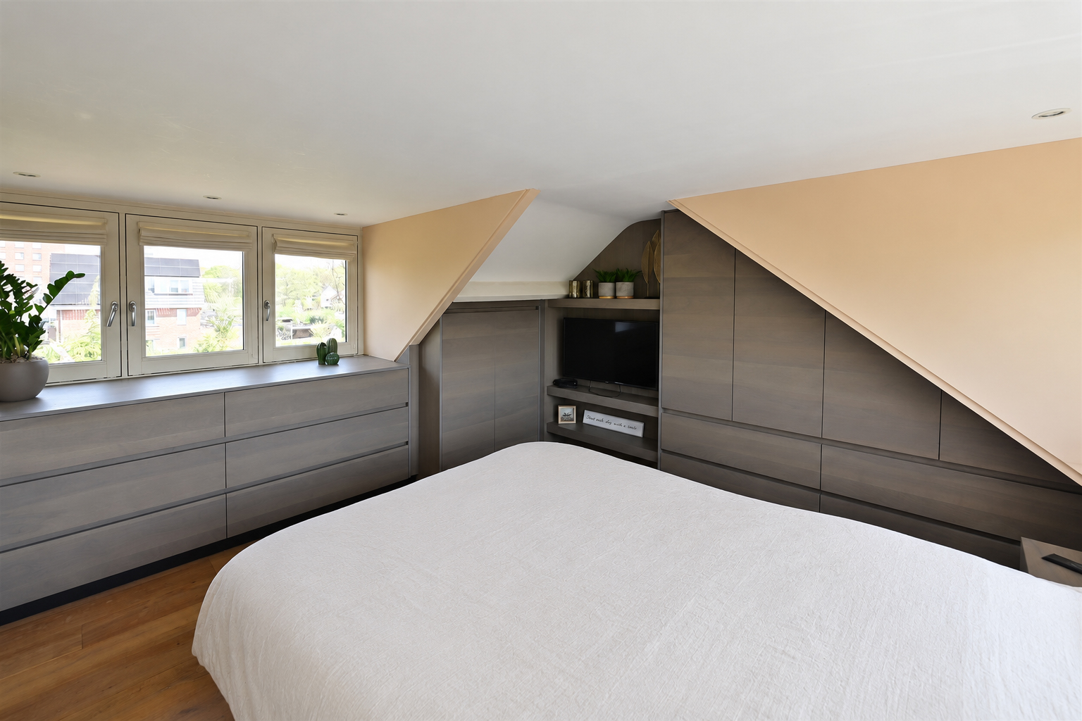Slaapkamer op zolder met inbouwkasten in dakkapel en schuine dak